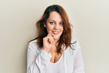 Young caucasian woman wearing casual clothes smiling looking confident at the camera with crossed arms and hand on chin. thinking positive.