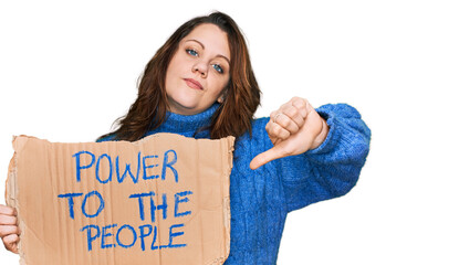 Young plus size woman holding power to the people banner with angry face, negative sign showing...