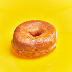  SIngle glazed doughnut over yellow background