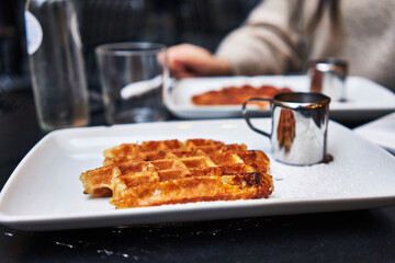  Two waffles and chocolate sauce on wooden surface