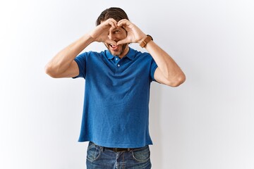 Fototapeta premium Handsome middle age man standing together over isolated background doing heart shape with hand and fingers smiling looking through sign