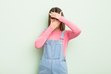 pretty young woman covering face with both hands saying no to the camera! refusing pictures or...