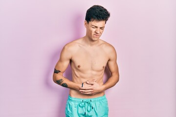 Fototapeta premium Young hispanic man wearing swimwear shirtless with hand on stomach because indigestion, painful illness feeling unwell. ache concept.
