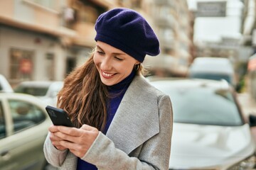 Young blonde woman smiling happy using smartphone at the city.