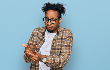 Young african american man with beard wearing casual clothes and glasses suffering pain on hands...