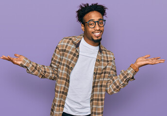 Young african american man with beard wearing casual clothes and glasses smiling showing both hands...