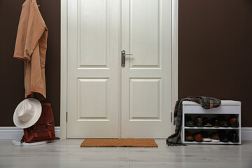 Shelving unit with shoes, coat rack and door mat in hall