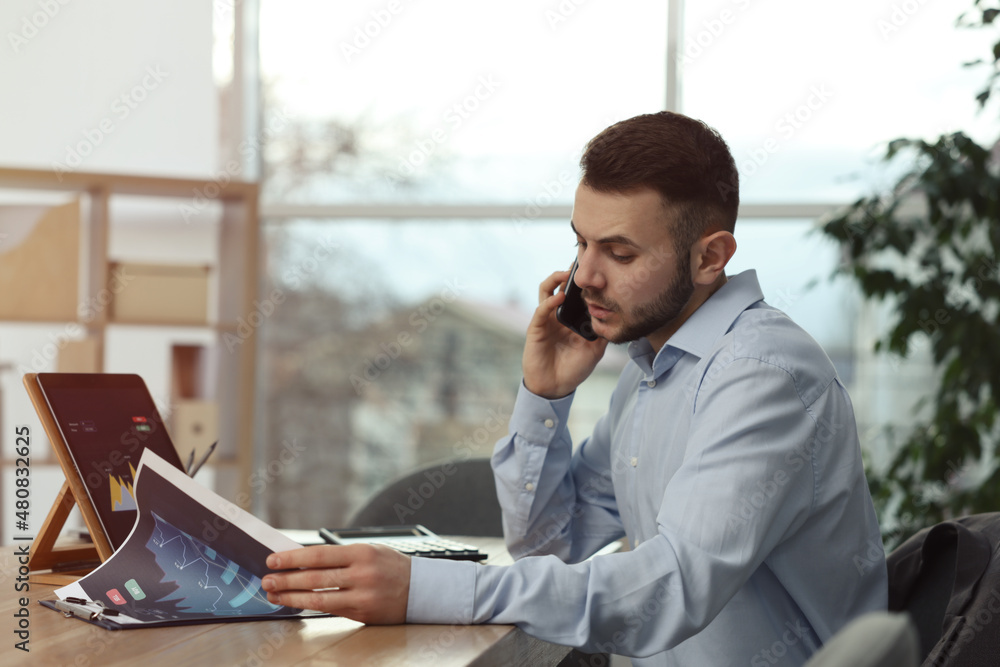 Poster forex trader talking on phone while working in office