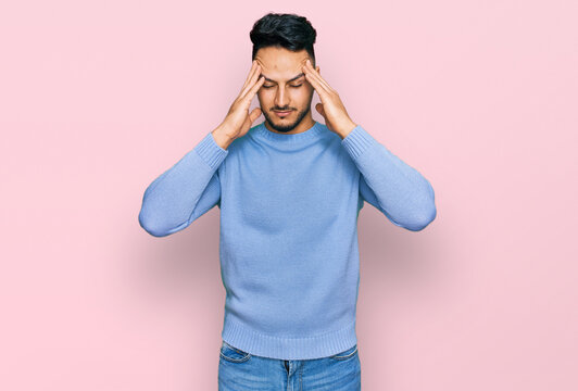 Young arab man wearing casual clothes suffering from headache desperate and stressed because pain and migraine. hands on head.