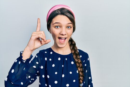 Young brunette girl wearing elegant look pointing finger up with successful idea. exited and happy. number one.