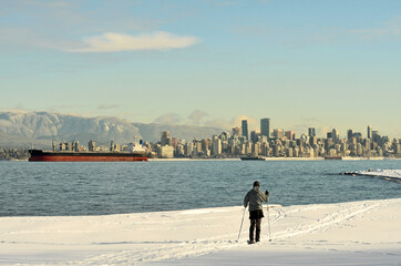 Man cross country skiing stopping to look at Vancouver winter scene.