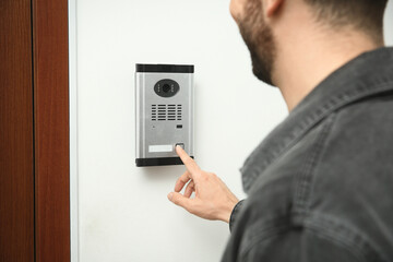 Man ringing intercom with camera in entryway, closeup