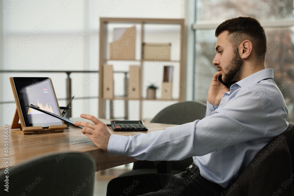 Poster forex trader talking on phone while working in office