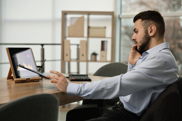 Forex trader talking on phone while working in office