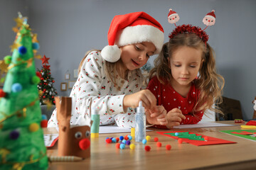 Cute little children making beautiful Christmas greeting cards at home