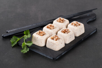 Vegan Cereal small snack, Buckwheat cream jelly in the form of square savarin on a serving board on a dark gray background