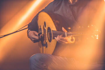 Toned image of musician playing traditional Turkish oud during concert