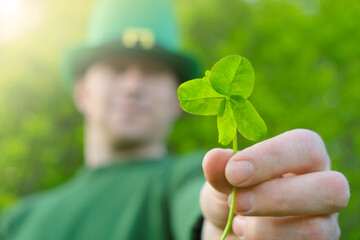 Saint Patrick background.Man in green leprechaun hat with clover flowers and the decorative flag of...