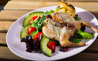 Photography of plate with quail-tobacco with sesame which served with salad of avocado and greenery...