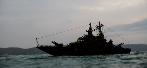 Silhouettes of a crowd standing at blurred military war ship on foggy background. Selective focus.