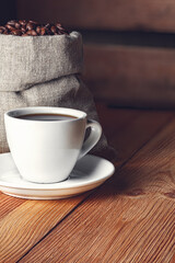 Coffee cup with saucer, beans and burlap bag