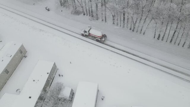 Top down view of gas truck during snowstorm on highway. Mobile home park covered in snow. Low visibility from all the heavy snow falling.
