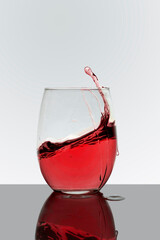 Crystal glass with red drink in motion with a white background