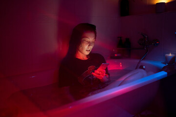 Unhappy asian woman addicted from social media read comments under ex-boyfriend photos sit in dark...