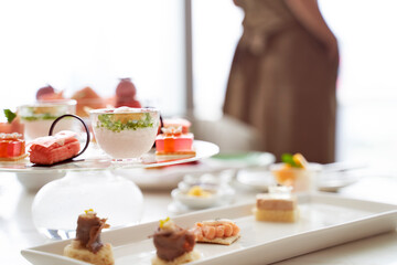 woman standing by window with assorted desserts on table