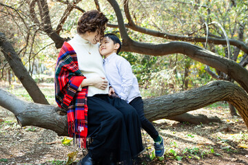 大きな木の上に座る妊娠中の母と、寄り添う幼い息子