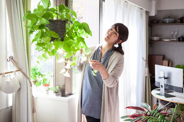 妊婦の女性が観葉植物に水やりをしている