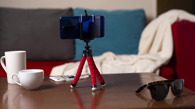 Stop motion animation with alive Phone Octopus Tripod puts on a smartphone, standing on the table in the home interior 