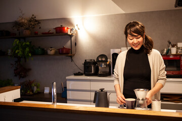 キッチンでコーヒーを淹れる妊婦の女性