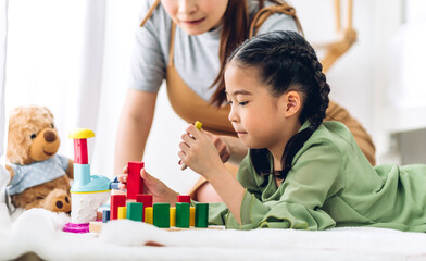 Obraz premium Portrait of enjoy happy love asian family mother and little asian girl smiling activity learn and skill brain training play with toy build wooden blocks board education game at home