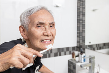 Healthy happy old elderly people brushing her teeth with toothbrush at bathroom in the...