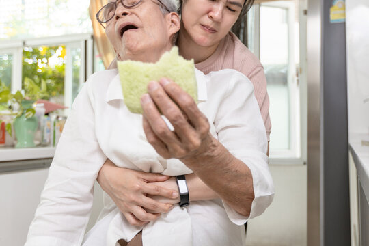 Senior woman with bread stuck in her throat,suffocating due to food clogging the trachea,obstruction of the airway,caregiver doing the heimlich maneuver,helping elderly,choking first aid,life support