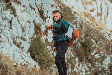 A male hiker looking at monitor watch checking heart rate during hiking on the mountain adventure...