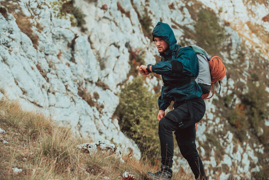 A male hiker looking at monitor watch checking heart rate during hiking on the mountain adventure travel extreme sport outdoor active lifestyle.