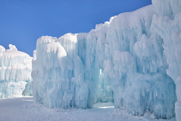 Clear blue sky on a winter day with huge icicles dripping on a giant frozen snow fort - obrazy, fototapety, plakaty