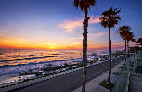People stop to watch the sun dip below the horizon at Windansea Beach, San Diego