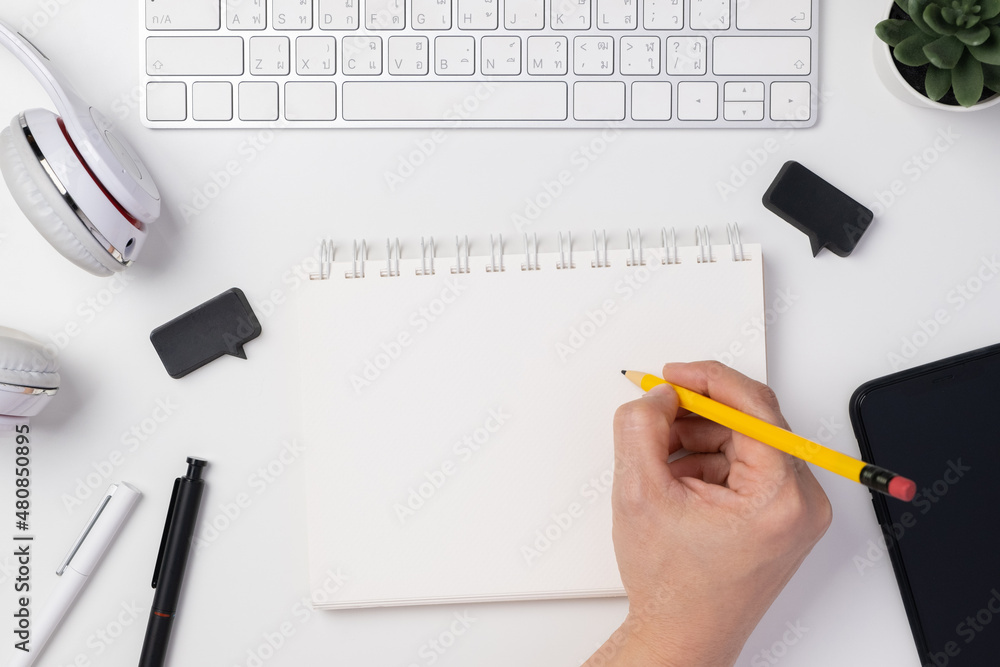 Poster top view hand writing on notebook working on desk with keyboard headphone on white table background