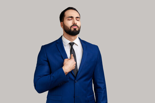 Portrait of bearded man pointing himself and looking selfish egoistic haughty, feeling proud of own achievement, wearing official style suit. Indoor studio shot isolated on gray background.