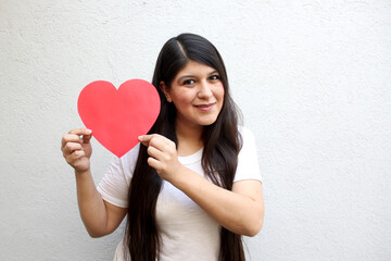 Latin adult woman shows her enthusiasm for the arrival of February and celebrate Valentine's Day of Love and Friendship with love and affection by giving
