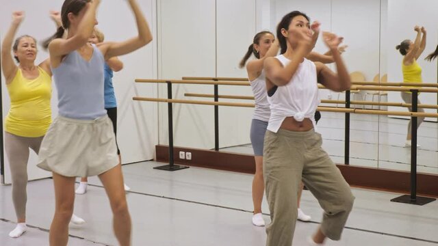 Positive women practicing vigorous dance movements in group dance class