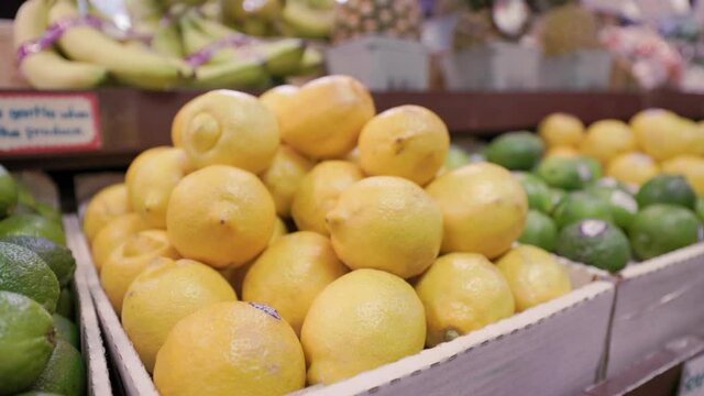 Lemon Crate in Grocery Store Aisle with Ripe Limes and other tropical Fruits