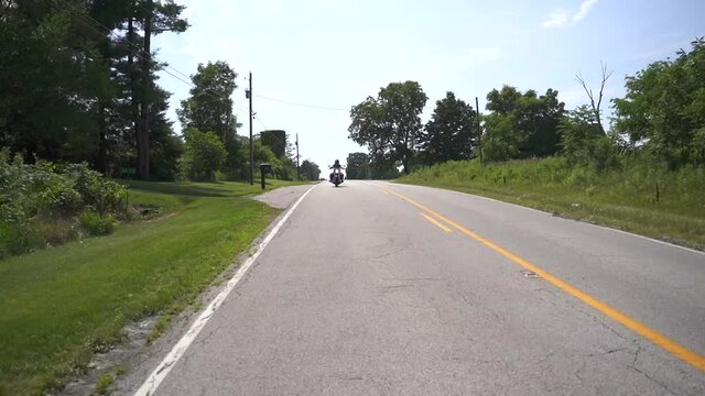Motorcycle Driving Down Country Road Towards Camera