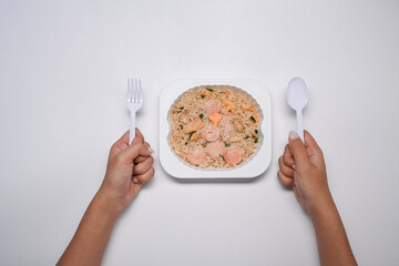 Woman holding spoon and fork ready to microwave and eat fried rice with shrimp.