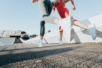 Two young fitness woman training running outdoors doing exercise wearing sportswear. Fitness girls...
