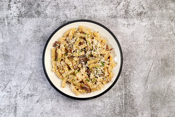 Pasta with beef stew and cheese on a round plate on a dark gray background. Top view, flat lay