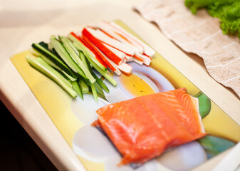 Making sushi and rolls at home. Sushi with seafood, salad and white rice. Food for family and friends. Sliced food and fish on a roll-making board